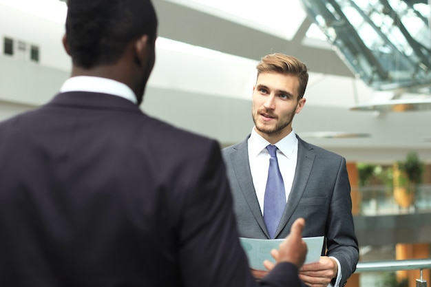 Zwei multinationale junge Geschäftsleute, die beim Treffen im Büro Geschäfte besprechen.