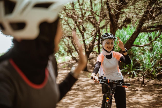 Zwei muslimische Frauen beim Radfahren winken sich beim Radfahren zu