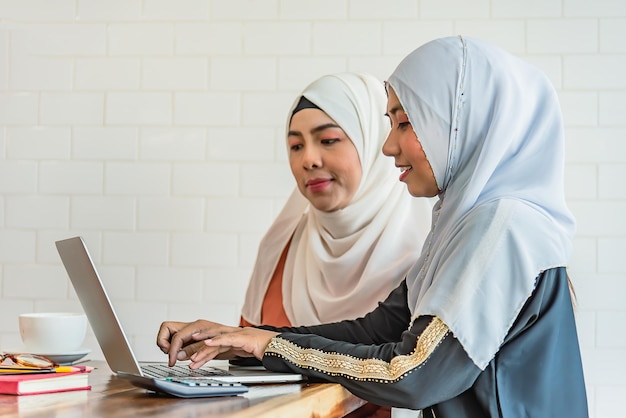 Zwei muslimische Frauen verwenden ein Computer-Notebook im sozialen Netzwerk des Internets zu Hause