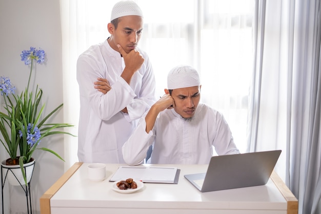 Zwei muslimische Geschäftspartner diskutieren und treffen sich mit Laptop zusammen