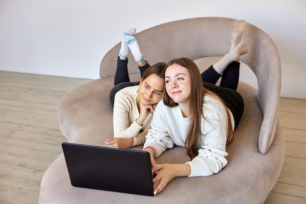 Zwei Nachbarn chatten mit Freunden mit Hilfe des Laptops in der Lounge