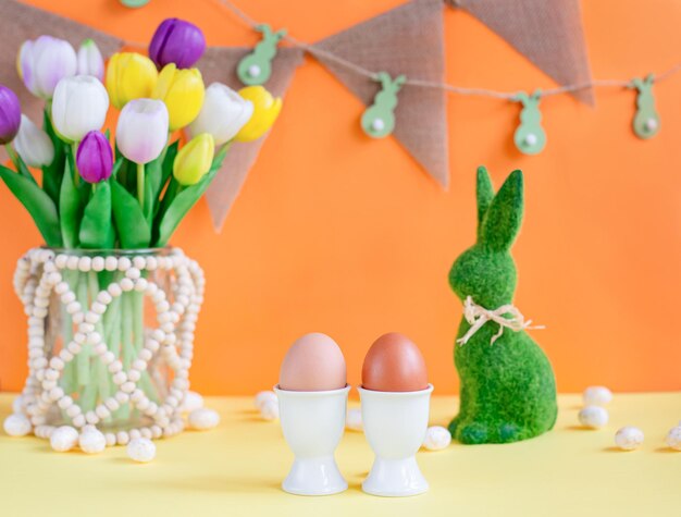 Zwei natürliche farbige Ostereier auf dem Hintergrund von Frühlingsblumen und einem Osterhase