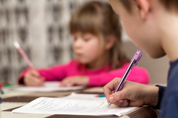 Zwei nette Kleinkinder, Junge und Mädchen, Bruder und Schwester, die zu Hause Hausarbeit tun, auf verwischt schreiben und zeichnen.