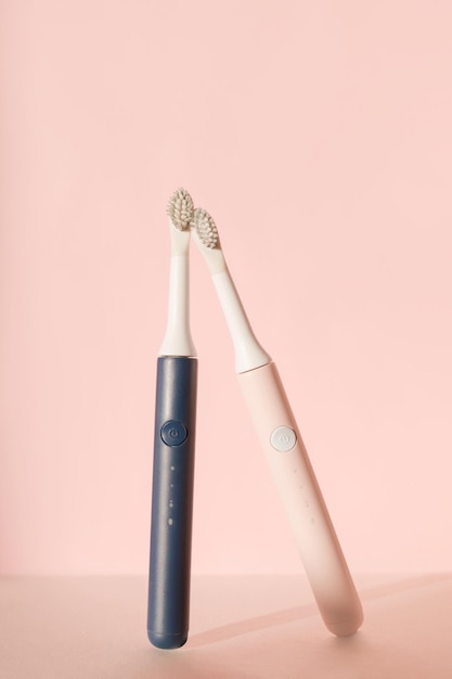 Zwei neue moderne Ultraschall-Zahnbürsten Zahnpflegeartikel auf rosa Pastellhintergrund Mundhygiene d ...