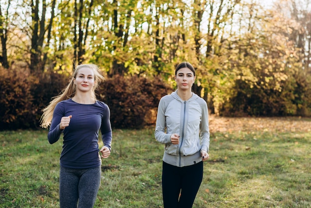 Zwei niedliche Fitness-Mädchen, die im Park joggen.