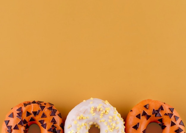 Zwei orangefarbene Donuts und ein weißer auf orangem Hintergrund