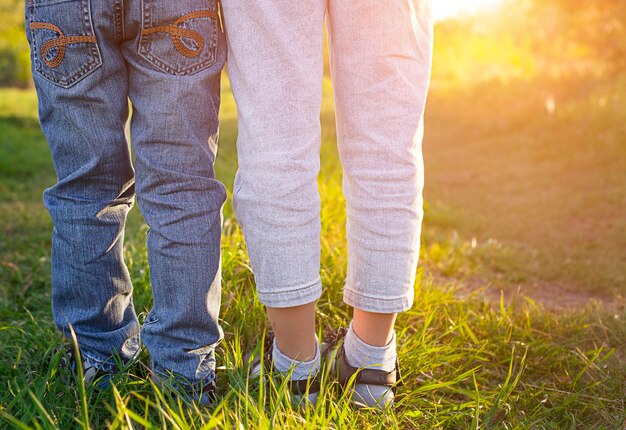 Zwei Paar Kinderbeine in Jeans Nahaufnahme im Freien in der Sonne