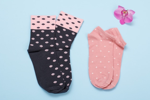 Zwei Paar schwarze und rosa Damensocken auf blauem Hintergrund, Ansicht von oben.