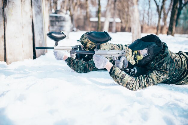 Zwei Paintballspieler liegen im Schnee