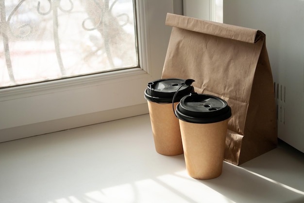 Zwei Pappbecher mit Kaffee und eine Papiertüte mit Brötchen auf dem Fensterkopierraum