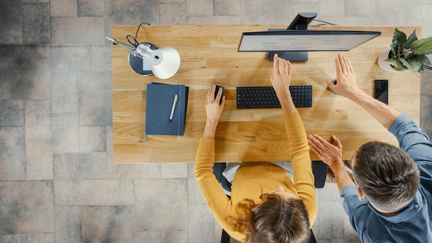 Zwei Personen arbeiten an einem Schreibtisch mit einem Schreibtisch und einem Computer