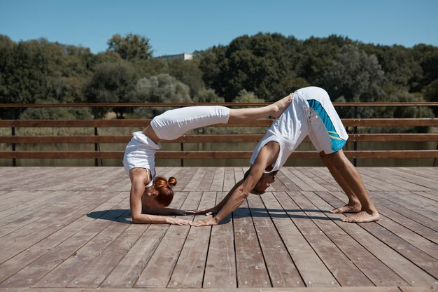 Zwei Personen, Mann und Frau, praktizieren Yoga im Park