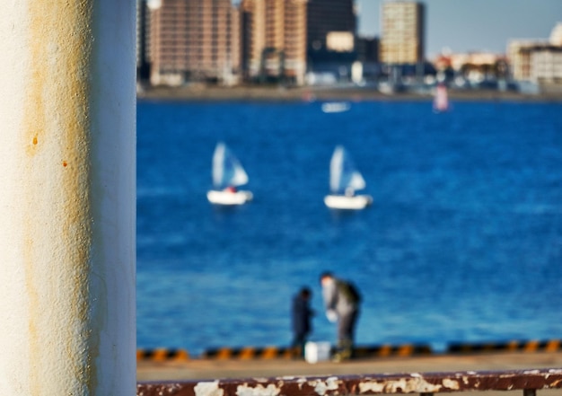 Foto zwei personen stehen in einem hafen vor dem meer und einer yacht