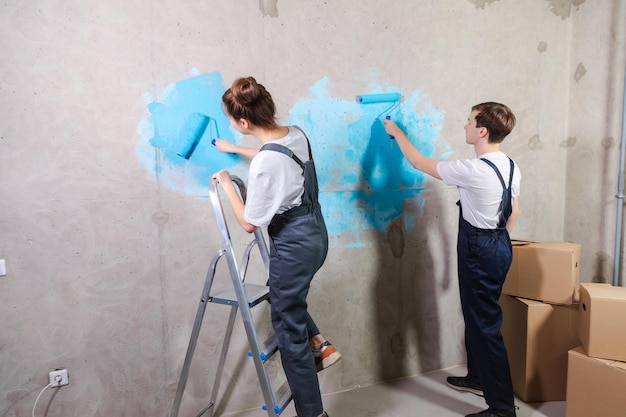 Zwei Personen streichen eine Wand mit blauer Farbe