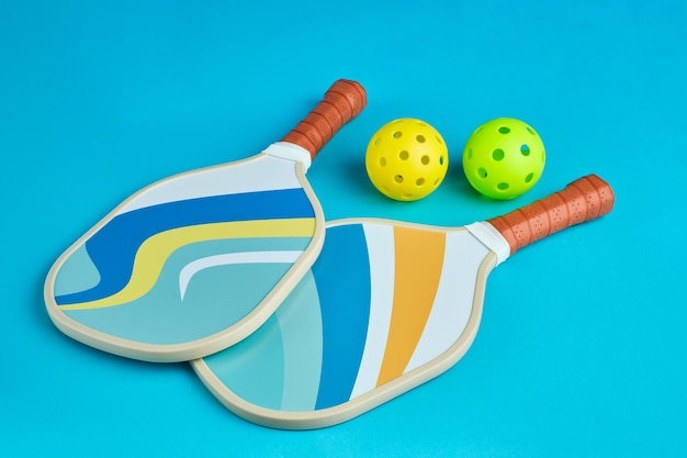 Foto zwei pickleball-paddles in blauen tönen auf einer blauen oberfläche mit zwei kugeln daneben