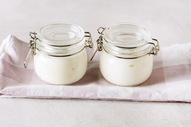 Zwei Portionen frischer natürlicher hausgemachter Bio-Joghurt in einem Glas Löffel grauer Hintergrund