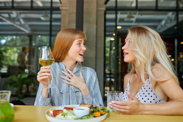 Zwei positive kaukasische Frauen verbringen gerne Zeit miteinander im Restaurant