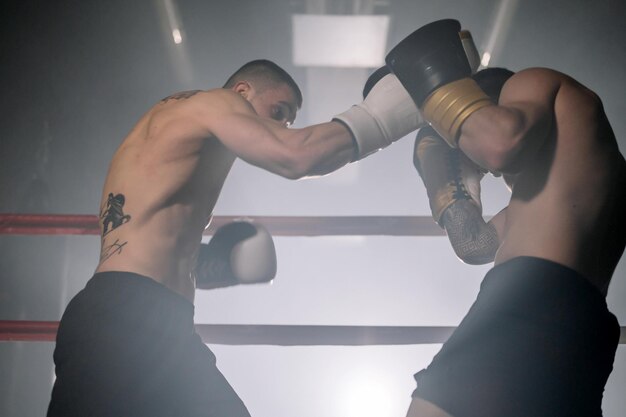 Foto zwei professionelle junge muskulöse hemdlose männliche boxer kämpfen in einem boxring hochwertige fotografie