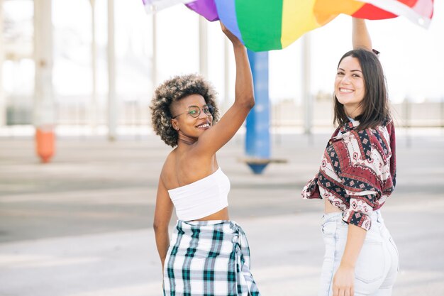 Zwei protestierende Freunde gehen glücklich, während sie eine LGBT-Flagge halten