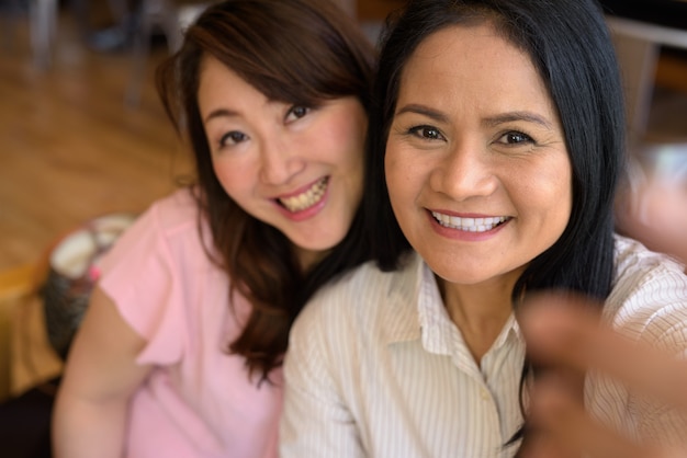 Zwei reife asiatische Frauen, die zusammen im Café herumhängen