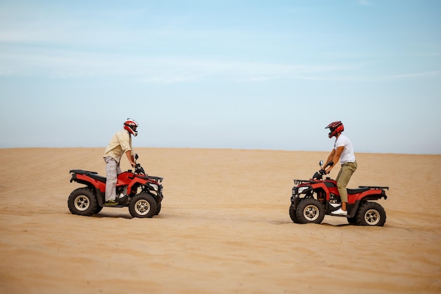 Zwei Rennfahrer in Helmen stehen sich auf ATVs gegenüber