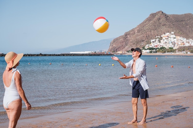 Zwei Rentner, die an einem sonnigen Tag Strandball spielen und ihren Ruhestand genießen Konzept Lifestyle Health Care Senior Sport