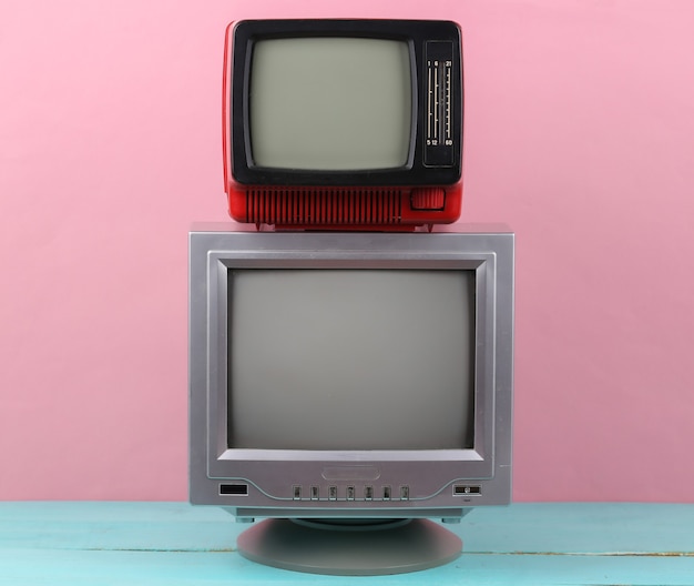 Zwei Retro-altmodische tragbare Fernseher auf rosa Hintergrund. Retro-Medien