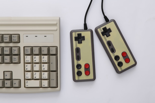 Zwei Retro-Gamepads und alte PC-Tastatur auf weißem Hintergrund. Gaming, Videospiel-Wettbewerb.