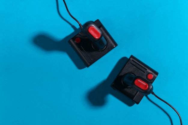 Zwei Retro-Joysticks auf blauem Hintergrund mit Schatten. Retro-Gaming. Ansicht von oben