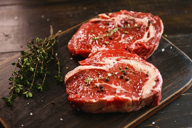 Zwei rohe Marmorsteaks in Olivenöl und Gewürzen zum Braten bereit.