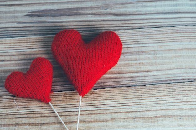 Zwei rote gestrickte Herzen auf hölzernem Hintergrund. Das Konzept des Valentinstags