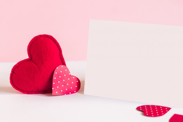 Zwei rote Herzen und ein weißes Blatt Papier