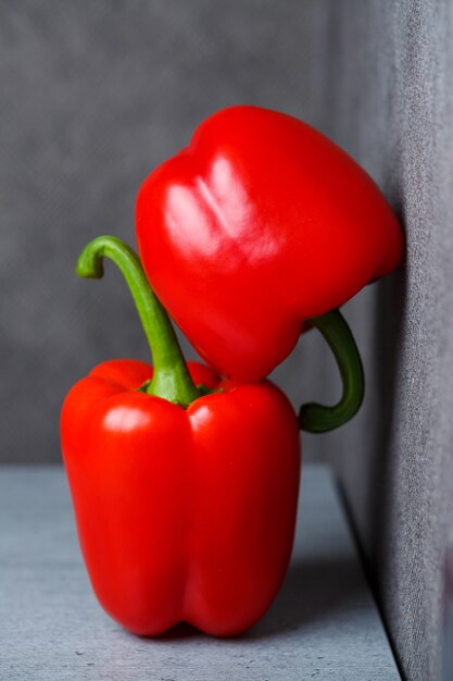 Zwei rote Paprika auf einem grauen Tisch