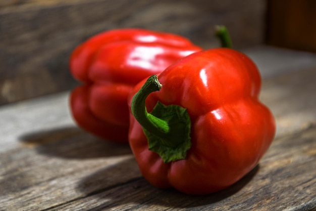 Zwei rote Paprika liegen auf einem Holztisch