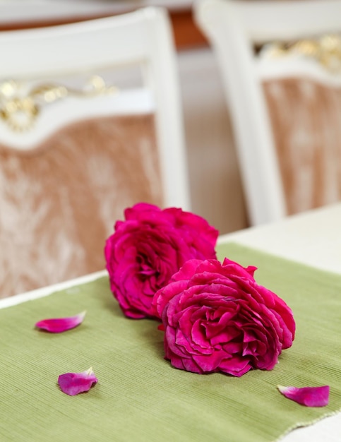 Zwei rote Rosen mit Blütenblättern auf dem Tisch