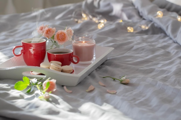 Zwei rote Tassen Kaffee und Blumen auf dem Bett