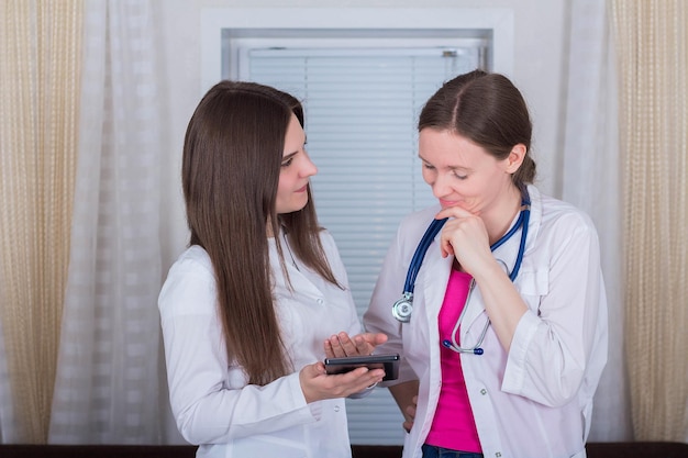 Zwei Ärztinnen oder Krankenschwestern schauen auf das Tablet und besprechen die Therapie