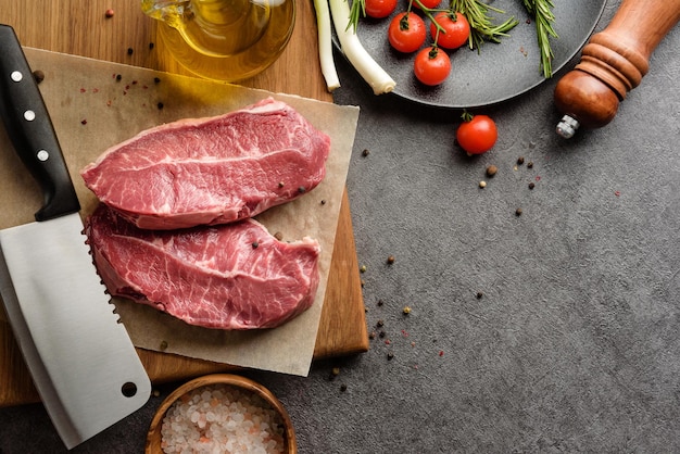 Zwei saftige Stücke marmoriertes Rindfleisch mit Gemüse und Kräutern Zutaten zum Kochen von Fleischgerichten