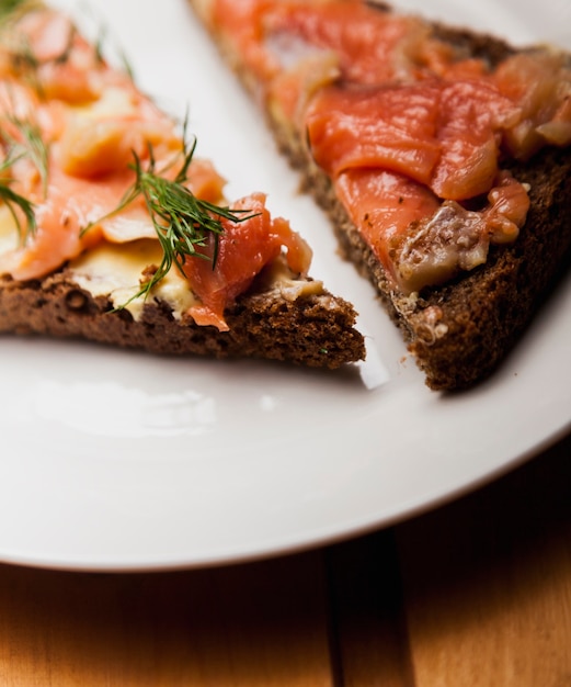 Zwei Sandwiches mit einem roten Fisch auf einem weißen Teller auf einem Tisch