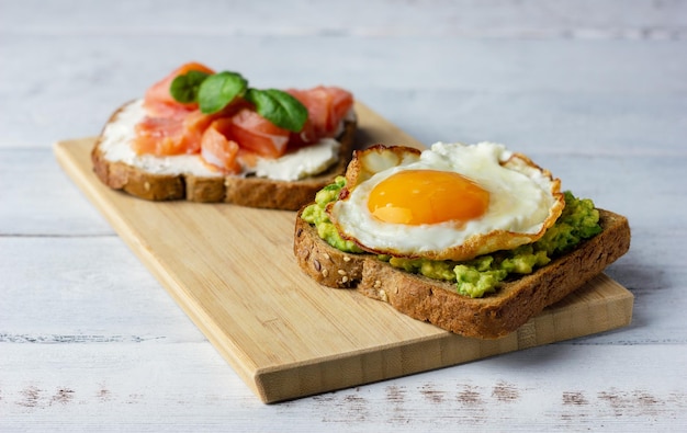 Zwei Sandwiches mit geräuchertem Lachs, Frischkäse, Avocado und Spiegelei Konzept für eine gesunde Ernährung