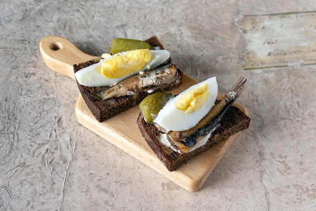 Zwei Sandwiches mit geräuchertem Saury auf einem Holzständer in der Nähe