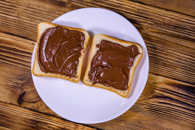 Zwei Sandwiches mit Schokoladenaufstrich auf einer weißen Platte Draufsicht