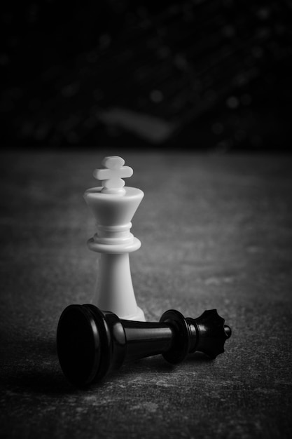 Zwei Schachfiguren sind König und besiegte Königin auf konkretem Hintergrund