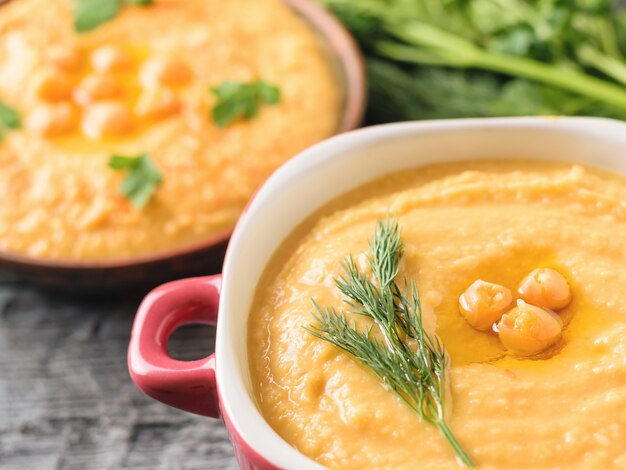 Zwei Schalen Hummus mit frischen Kräutern auf einem rustikalen Tisch