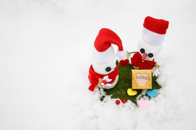 Foto zwei schneemänner auf weißem hintergrund. schneemänner geben geschenke zum valentinstag. liebes-box zum valentinstag