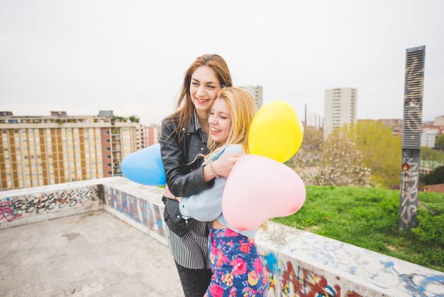 Zwei schöne Blondinen- und Brunettemädchen, die mit baloons spielen