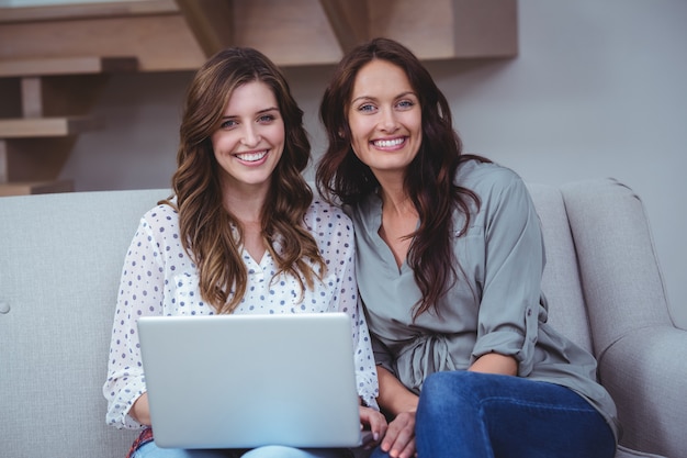 Zwei schöne Frauen, die einen Laptop im Wohnzimmer verwenden