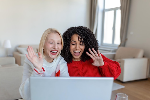 Zwei schöne Frauen mit Laptop für einen Online-Videoanruf und Online-Toast mit ihren Freunden Online-Party für Freunde