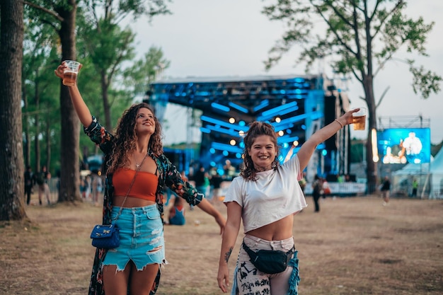 Foto zwei schöne freunde, die bier trinken und spaß auf einem musikfestival haben