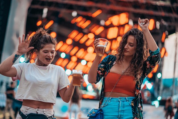 Zwei schöne Freunde, die Bier trinken und Spaß auf einem Musikfestival haben